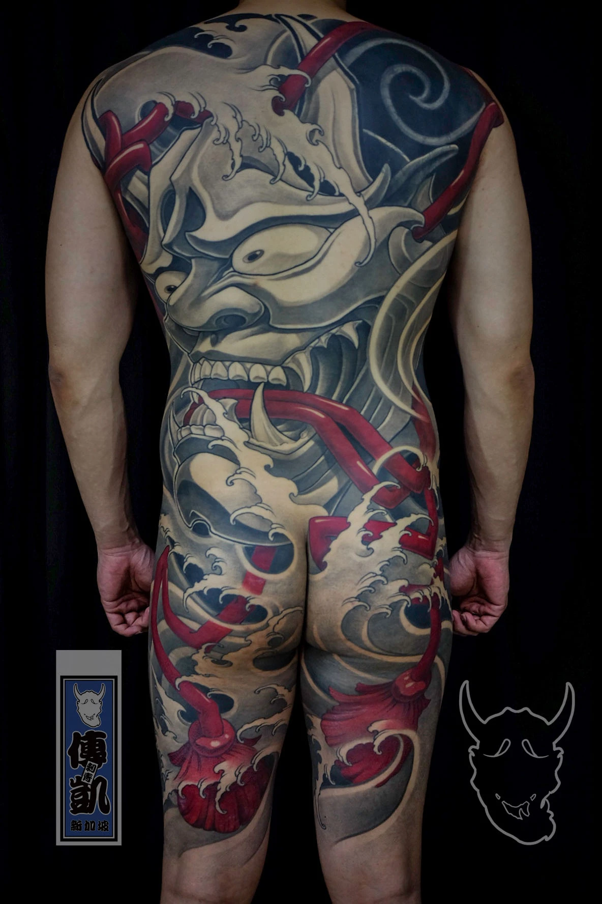 Japanese full back tattoo of a Hannya mask with red ropes and wave motifs, representing emotion, struggle, and transformation in traditional Irezumi art.