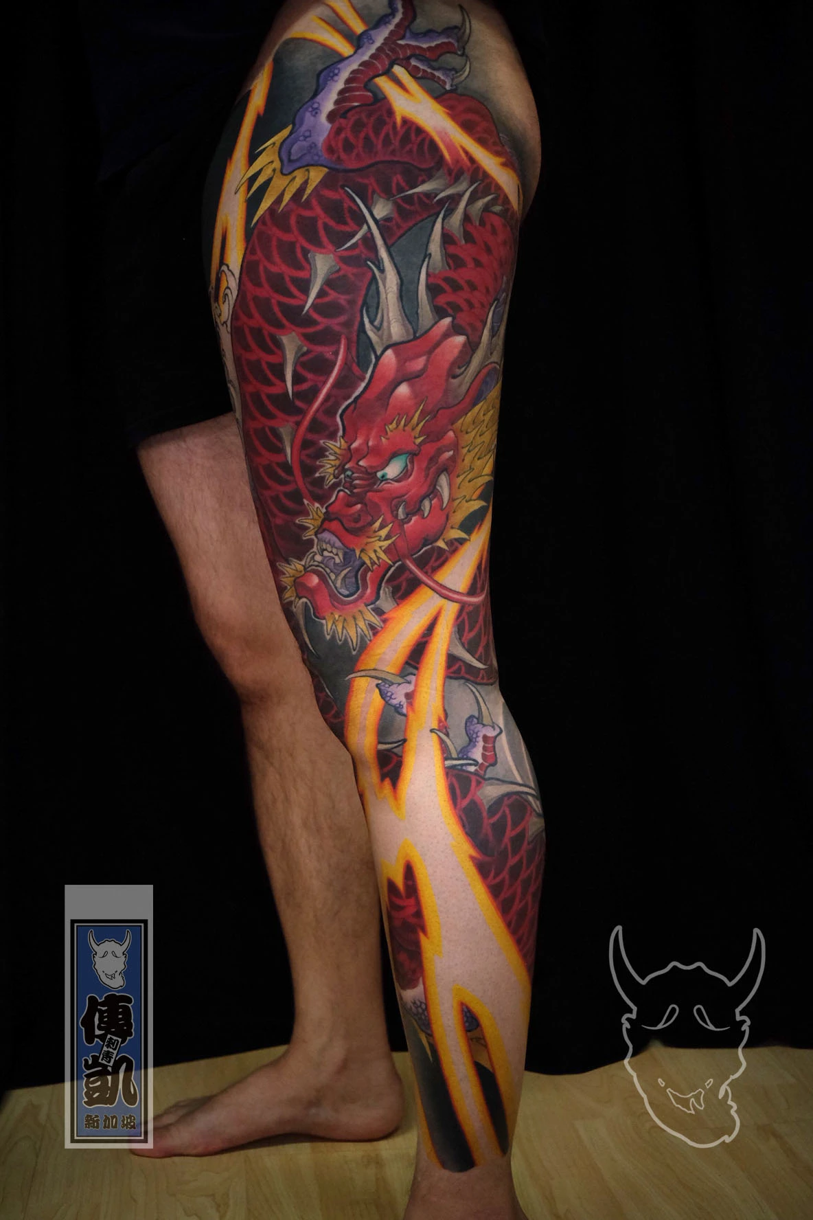 New Traditional Japanese red dragon tattoo on the leg, featuring bold red scales, dynamic lightning, and flowing wind bars — a modern take on traditional Japanese tattoo art.