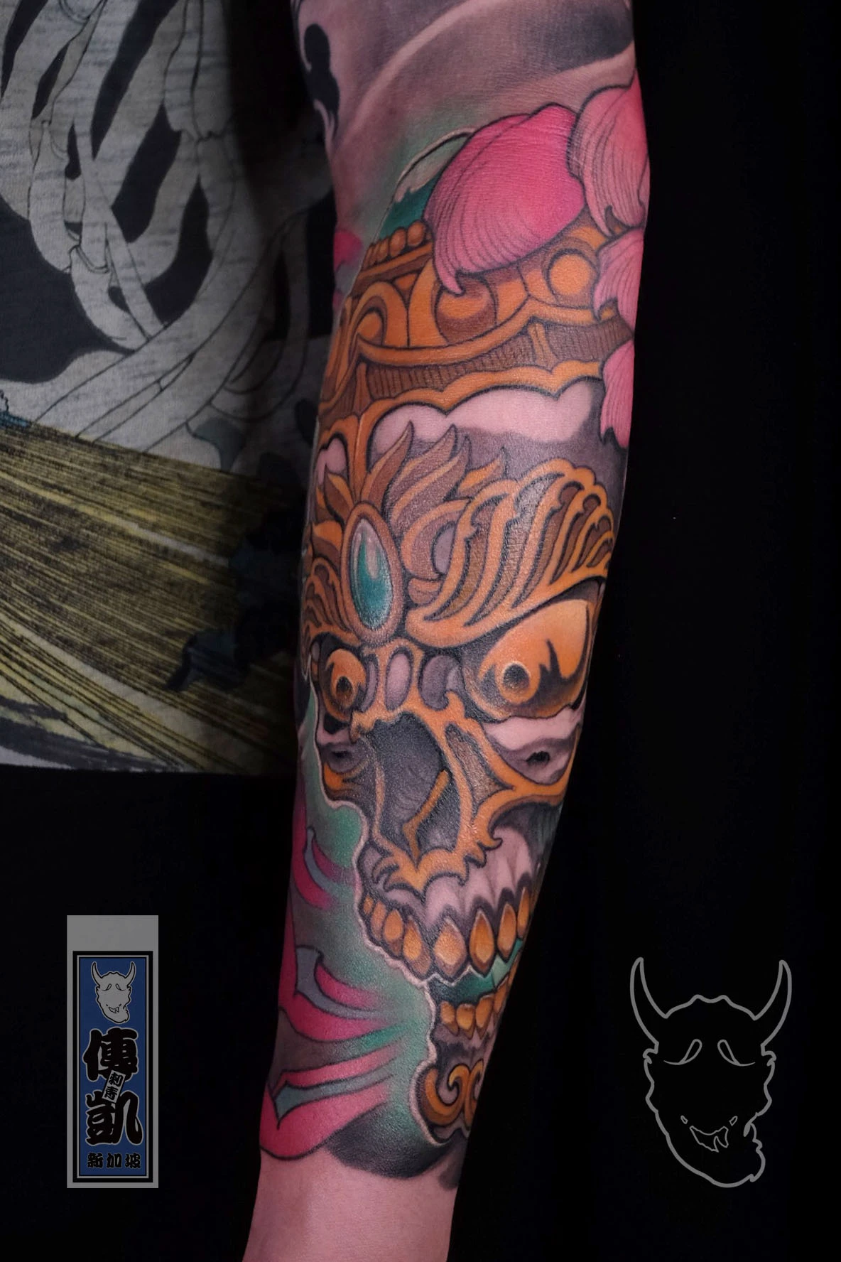 Traditional Tibetan skull tattoo on the forearm featuring ornate golden detailing, turquoise gem, and smoke patterns in Japanese irezumi style. Artwork by CK Tattoo Singapore.
