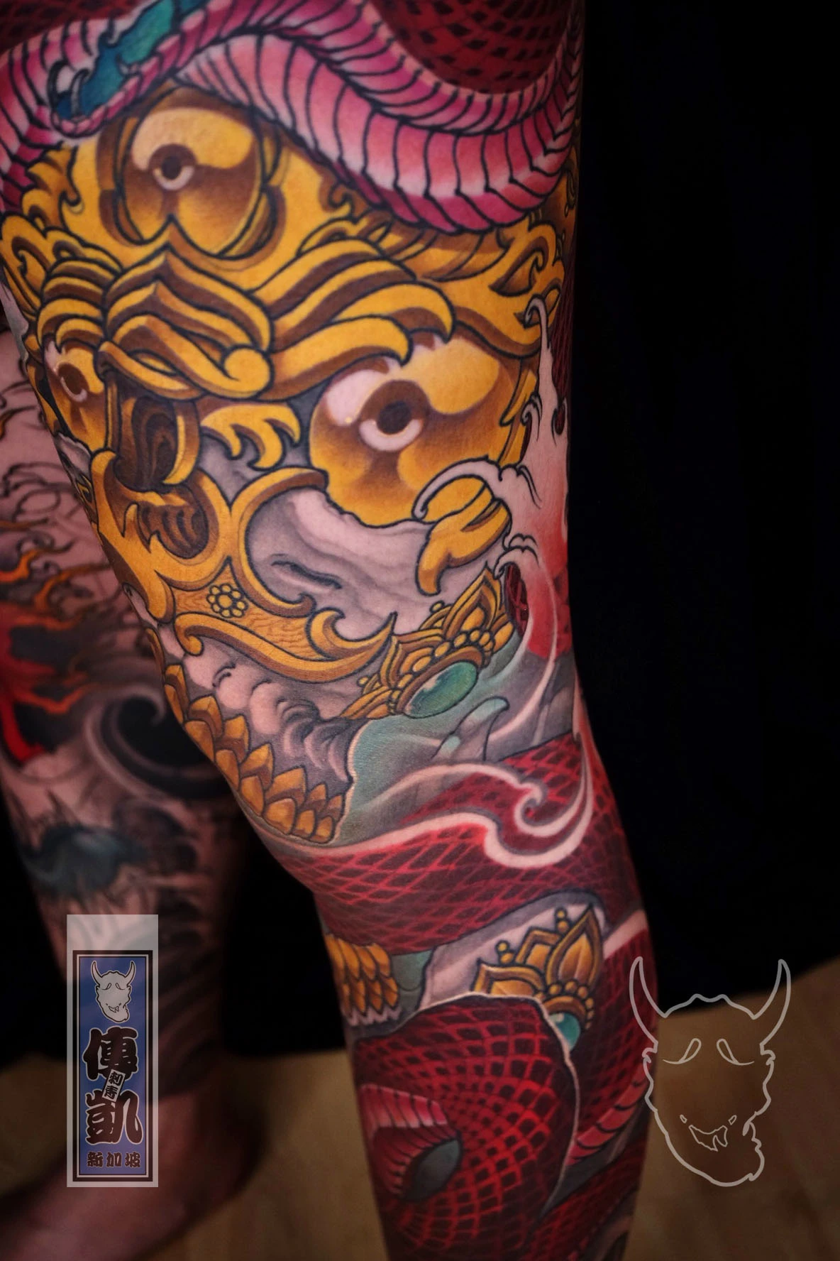 New Traditional Japanese leg tattoo of a red snake entwined around a golden Tibetan skull, symbolizing power and transformation. CK Tattoo Singapore.