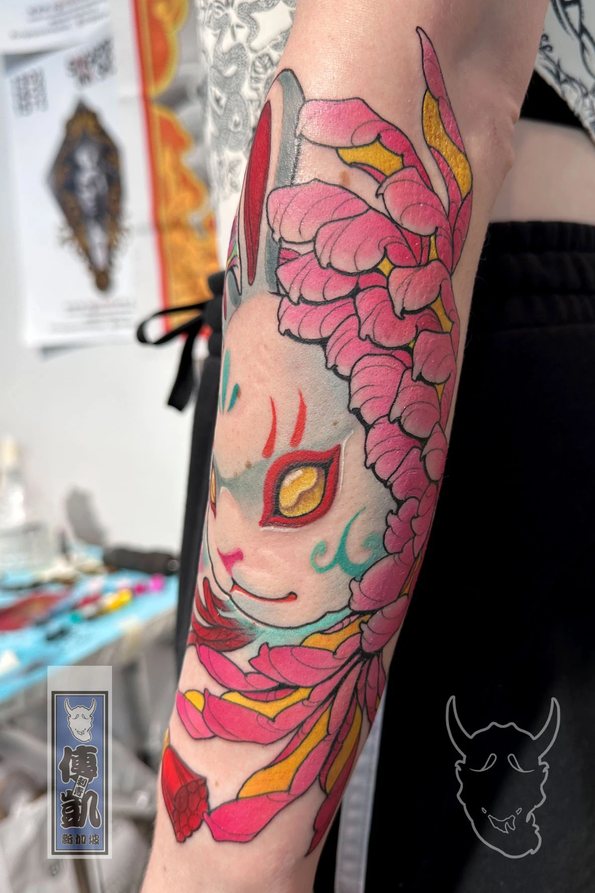 Japanese Usagi rabbit and kiku flower tattoo on forearm with red ribbons and pastel tones, symbolizing endurance and grace. Artwork by CK Tattoo Singapore.